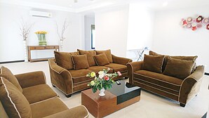 Een moderne woonkamer met een bruine zithoek, een bijpassende fauteuil en een salontafel met een bloemistdecoratie.
