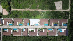 Luchtbeeld van een woongebied met meerdere huizen, elk met een zwembad en een tuin.