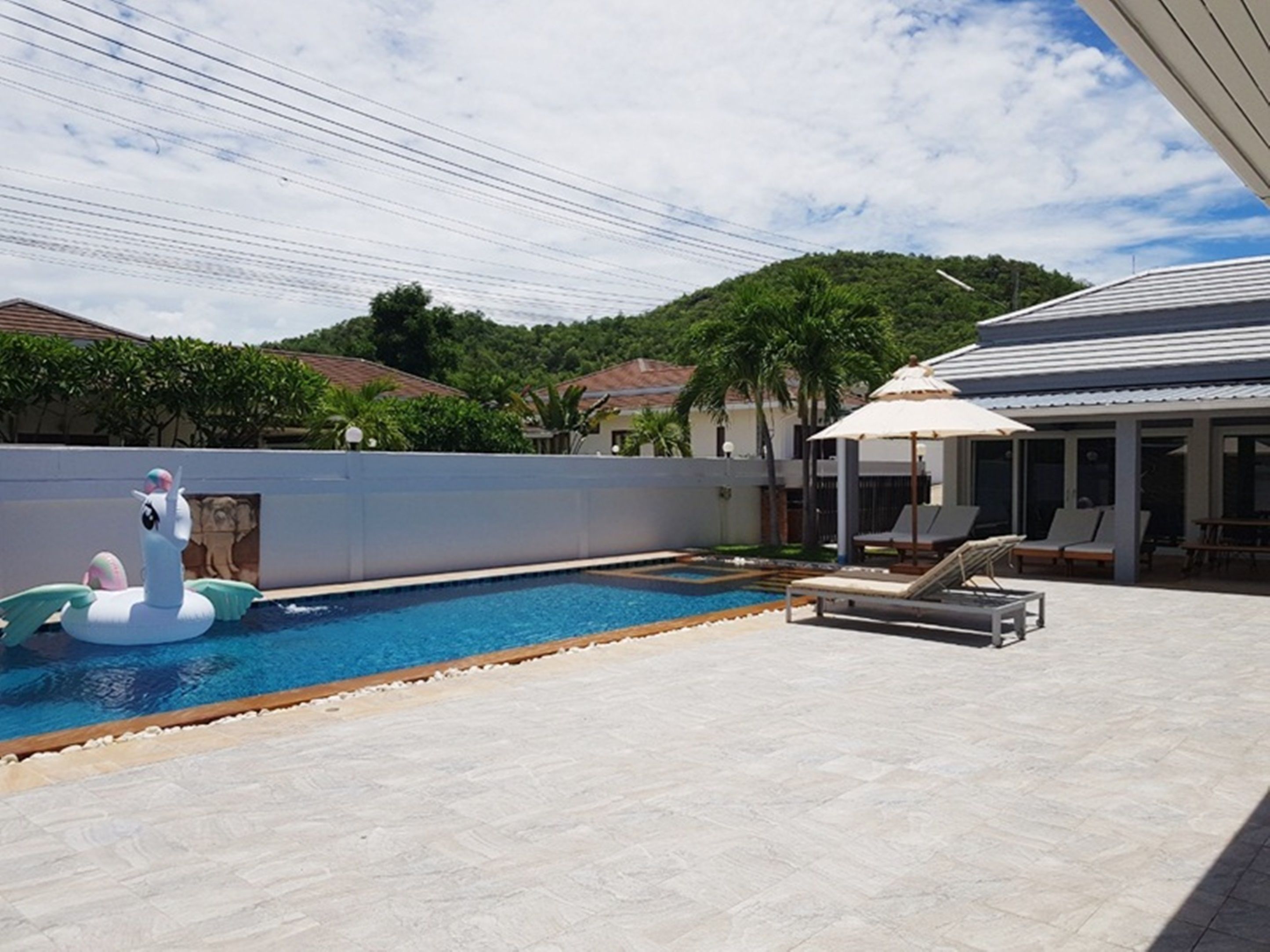 A swimming pool with lounge chairs and a covered seating area.