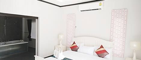 A hotel room with a bed, a nightstand, a lamp, a shower area, and a wall-mounted air conditioner.