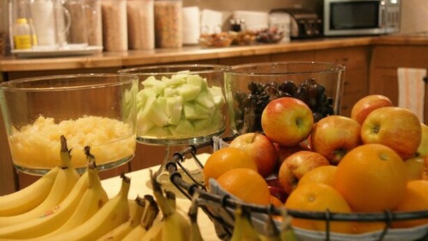 A kitchen counter with various fruits and a coffee maker. - R & R Inn & Suites (Camrose)