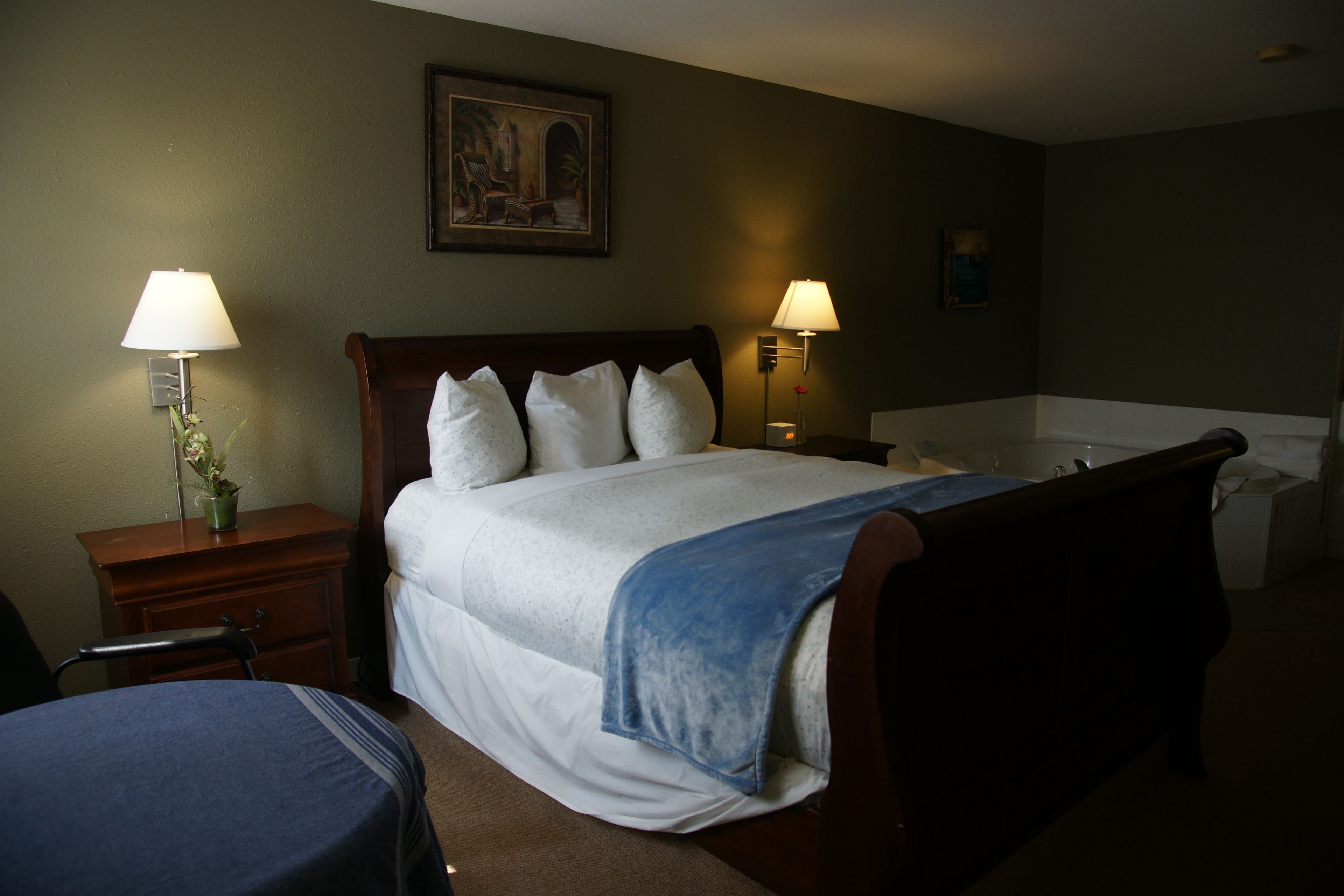 A hotel room with a bed, two bedside tables, a desk, a chair, and a bathroom.