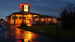 A motel with a prominent sign, a covered parking area, and a well-lit entrance. - R & R Inn & Suites (Camrose)