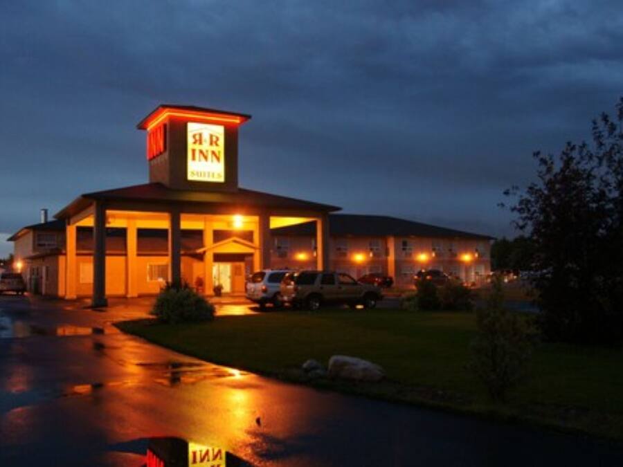 A motel with a prominent sign, a covered parking area, and a well-lit entrance.