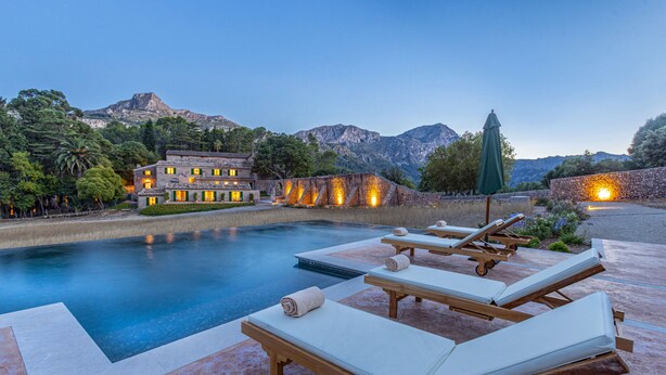 A pool area with lounge chairs and a building with illuminated windows. - Son Grua Agroturismo - Adults Only (Pollenca)