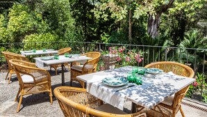 An outdoor patio with wicker furniture and white tablecloths, surrounded by lush greenery. - Son Grua Agroturismo - Adults Only (Pollenca)