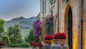 A courtyard with potted plants and a building with an arched doorway. - Son Grua Agroturismo - Adults Only (Pollenca)