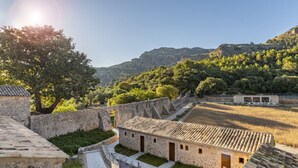 A stone building with a tiled roof, surrounded by a stone wall and greenery. - Son Grua Agroturismo - Adults Only (Pollenca)