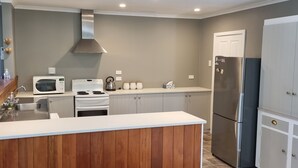 A modern kitchen with a central island, stainless steel appliances, and a grey wall.