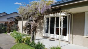 A residential house with a large front window, a covered porch, and a well-maintained garden.