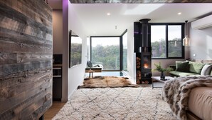 Un intérieur moderne avec un grand lit, une cheminée et une vue sur l’extérieur.