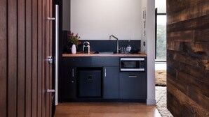 Une cuisine moderne avec des meubles de rangement aux couleurs sombres, un évier en acier inoxydable et un four à micro-ondes encastré.