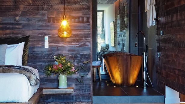 Une salle de bain moderne avec un meuble-lavabo en bois, une grande baignoire et un espace douche.