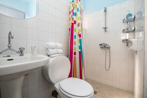 Kylpyhuone, jossa on valkoinen pesuallas, wc ja suihkutila.