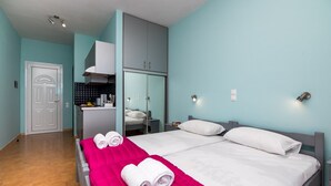 A hotel room with a bed, two pillows, a red blanket, and two rolled towels. - Lourdas amazing view - Studio Marinos. (Vlachata)