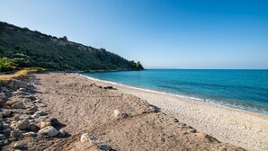 A beach with a rocky shoreline and a forested hillside in the background. - Lourdas amazing view - Studio Marinos. (Vlachata)