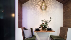 A cozy seating area with a wooden bench and cushioned seats, a small table with a vase of flowers, and a hanging light fixture. - Ranked in the World's Top 60 Places to Elope (Hepburn Springs)