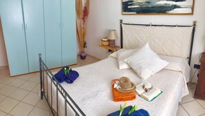 Een net opgemaakt bed met een witte dekbedovertrek, een blauwe handdoek en een bruin geweven item.