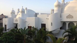 Un edificio blanco con múltiples cúpulas y torres, rodeado de palmeras.