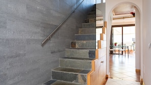 Una escalera de piedra con barandillas de madera que conduce a un espacio interior con comedor y vistas al exterior.