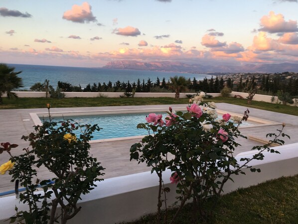 A swimming pool with a view of the sea and mountains in the background.