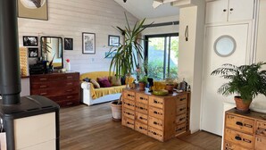 Ein gemütliches Wohnzimmer mit Sofa, Holzschrank und einem großen Fenster.