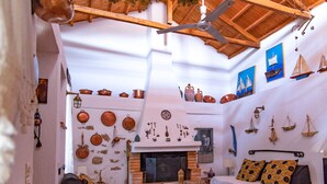 A cozy living room with a fireplace, two sofas, and a ceiling fan. - Country Villa Kalimera | Private Hilltop Villa in Skopelos with Pool & Views (skopelos)