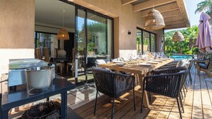 An outdoor dining area with a wooden table, black chairs, and a large pot on a table. - House / Villa - SAINT-TROPEZ (La Croix-Valmer)