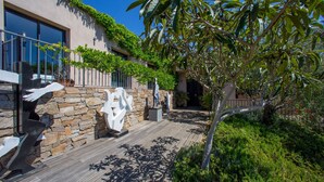 A modern outdoor area with a stone wall, wooden deck, and greenery. - House / Villa - SAINT-TROPEZ (La Croix-Valmer)