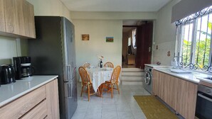 Cozinha compacta com área de refeições, geladeira, cafeteira e janela com vista.