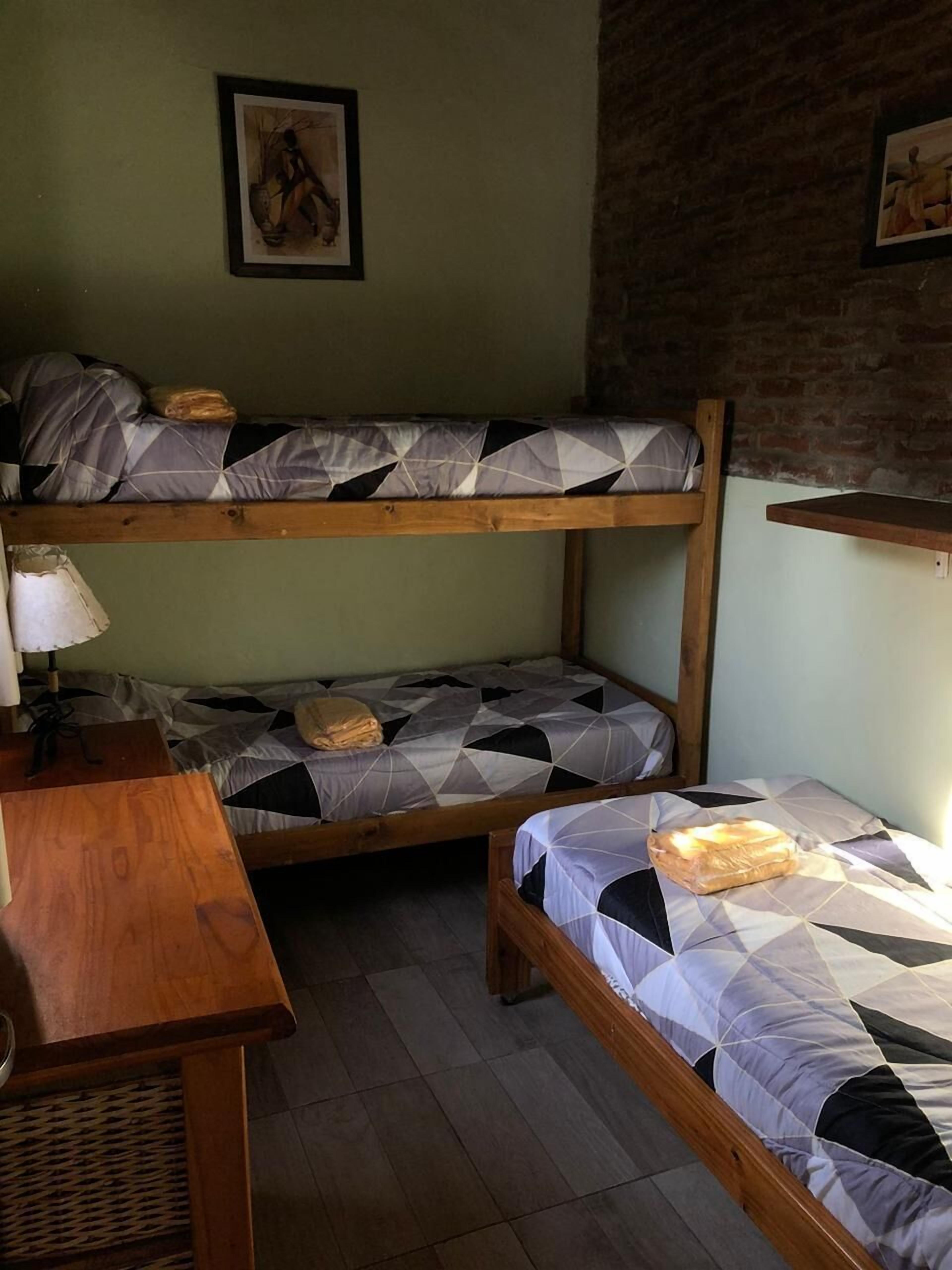 Une chambre de dortoir avec deux lits superposés, un bureau en bois et une lampe.