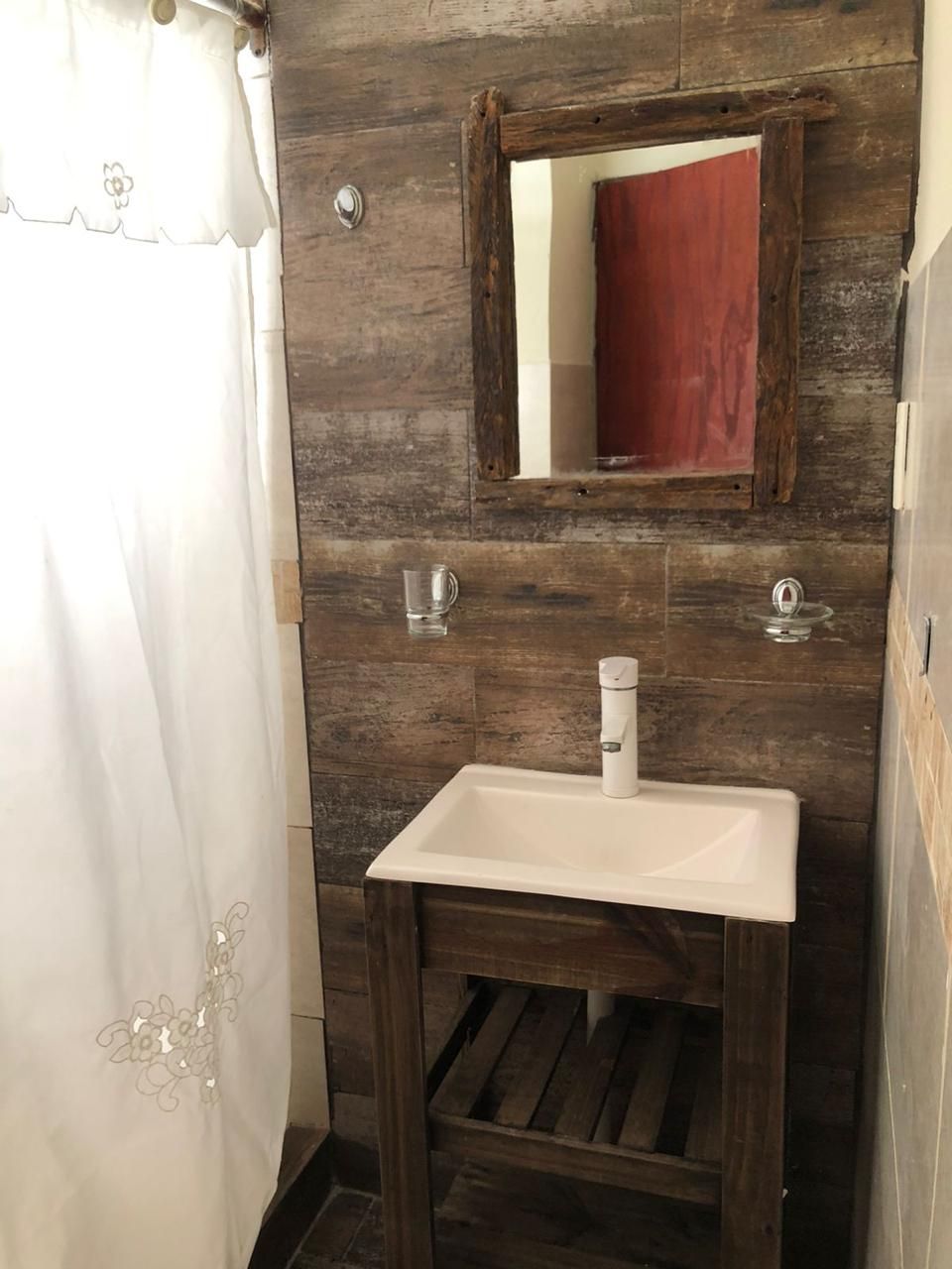 A bathroom with a wooden wall, a white sink, and a mirror.