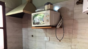 A kitchen with a stove, microwave, sink, and wooden cabinets.