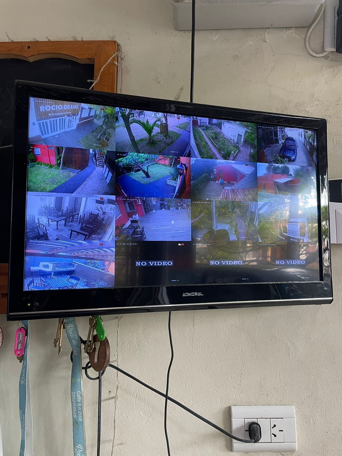 A flat-screen TV mounted on a wall displaying multiple security camera feeds.