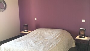 A bedroom with a large bed, purple walls, and two bedside lamps. - Bedroom ADVENTURE Villa AMALIA (PORTICCIO)