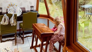 A cozy room with a large window, wooden furniture, and a patterned wallpaper.