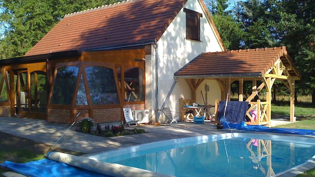 A house with a swimming pool, a covered porch, and a wooden deck.