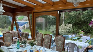 A covered patio with a dining table set for six, surrounded by floral-patterned chairs.