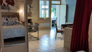 Ein geräumiges Zimmer mit einem großen Bett, einem Essbereich und Blick ins Freie.