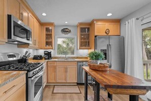 A modern kitchen with wooden cabinets, stainless steel appliances, and a wooden dining table.