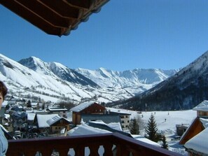 A mountain village with snow-covered houses and a clear view of snow-capped mountains.