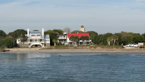 Una casa costera con techo rojo, una torre de campanas y un balcón con vista a la playa.