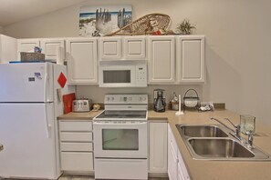 Une cuisine compacte équipée d’un réfrigérateur, d’un four à micro-ondes, d’une cuisinière et d’un évier à deux bacs.