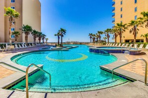Relax by the pool surrounded by palm trees and lounge chairs on a tiled deck.
