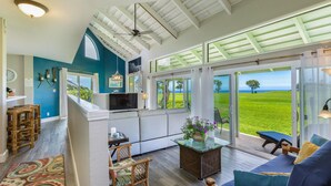 A modern kitchen with a large island, a dining area with a view, and a cozy seating area with a view of the ocean. - Kauai Sunrise, Rainbows, Ocean Views & 15th Fairway of Makai (Princeville)