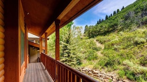 Eine Holzhütte mit einer Holzdar Terrasse und einer Steinsäule.