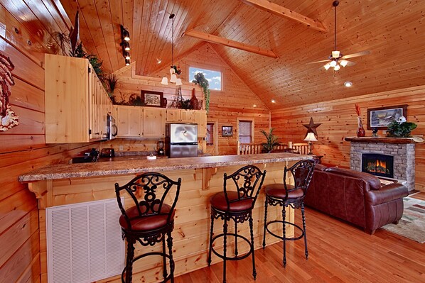 A log cabin interior with a kitchen, bar area, and seating.