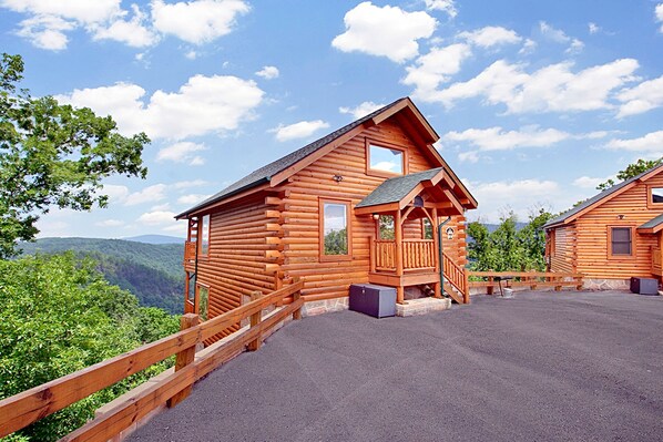 Eine Holzhütte mit Balkon, überdachter Picknickplatz und Bergblick.
