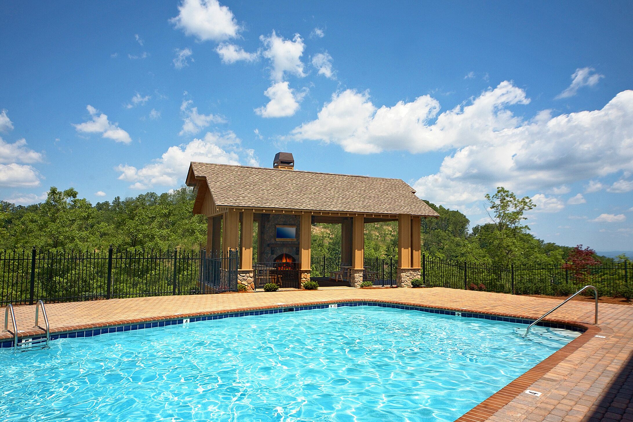 Une piscine dotée d’un pavillon couvert, de piliers en pierre et d’une terrasse en briques.