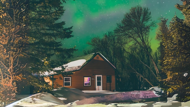 A cabin with a snow-covered ground, surrounded by trees, under a night sky with visible stars and green aurora. - Cozy 1BR Lakefront Cabin w/ Private Launch & Dock (Backus)